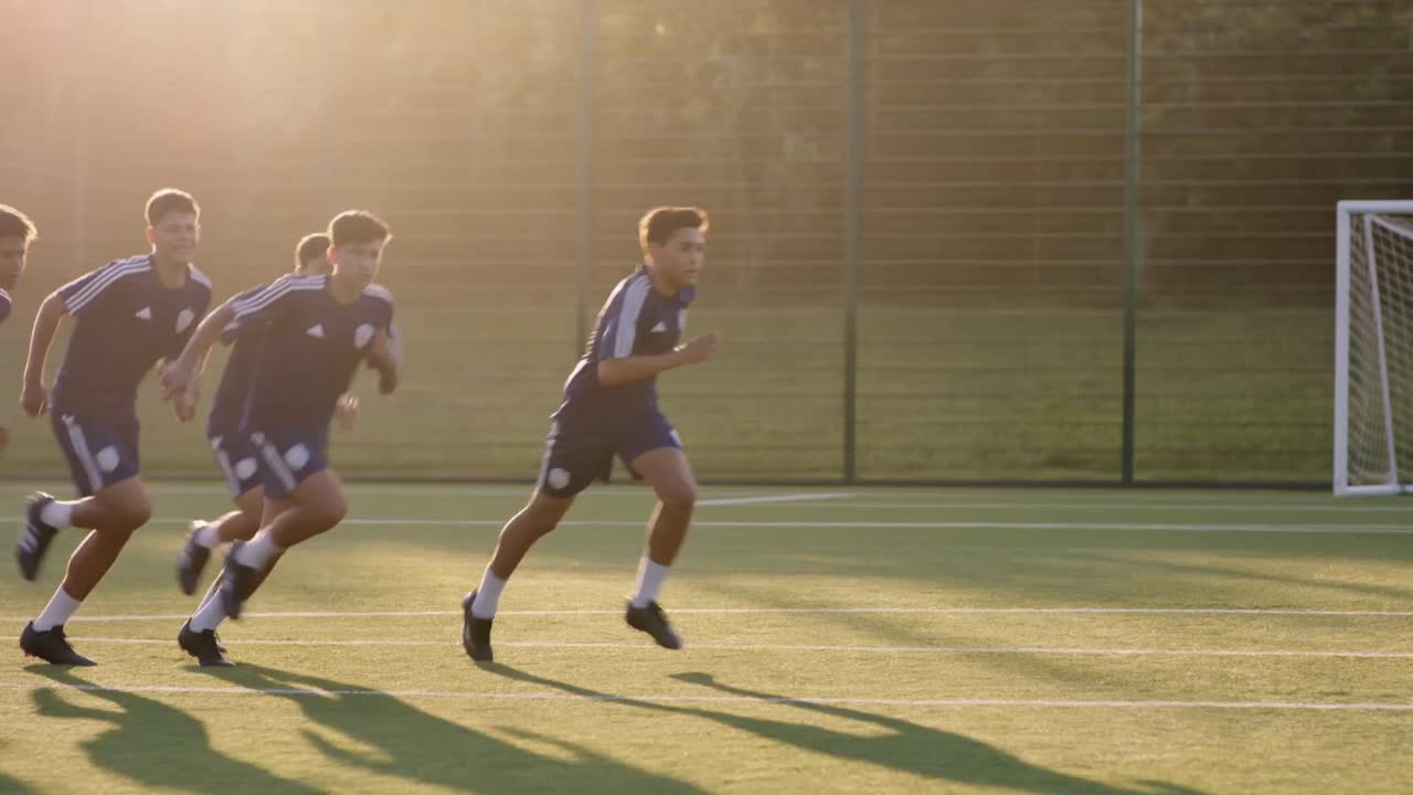 Young players warming up on the artificial pitch in the evening sun